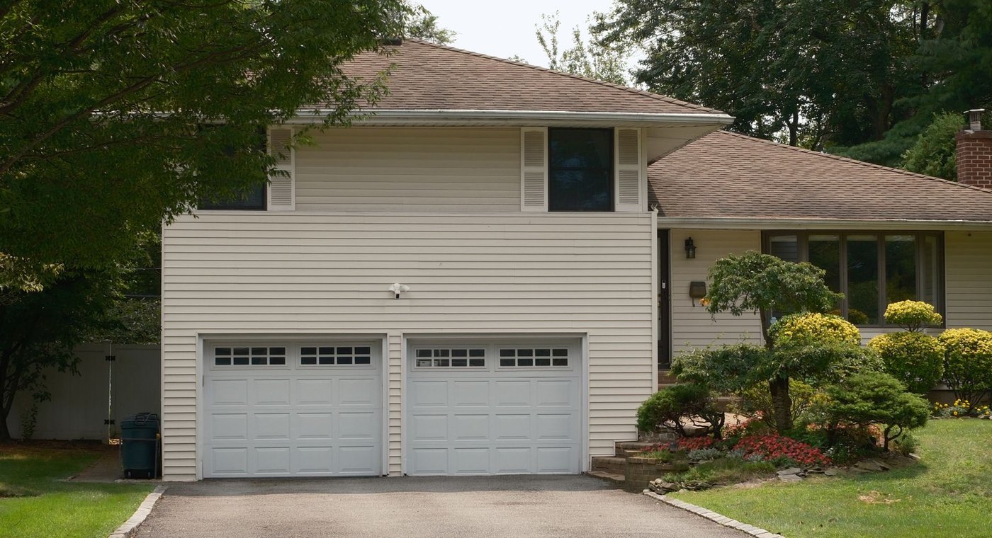 A two-car garage with white raised-panel sectional doors on a suburban house