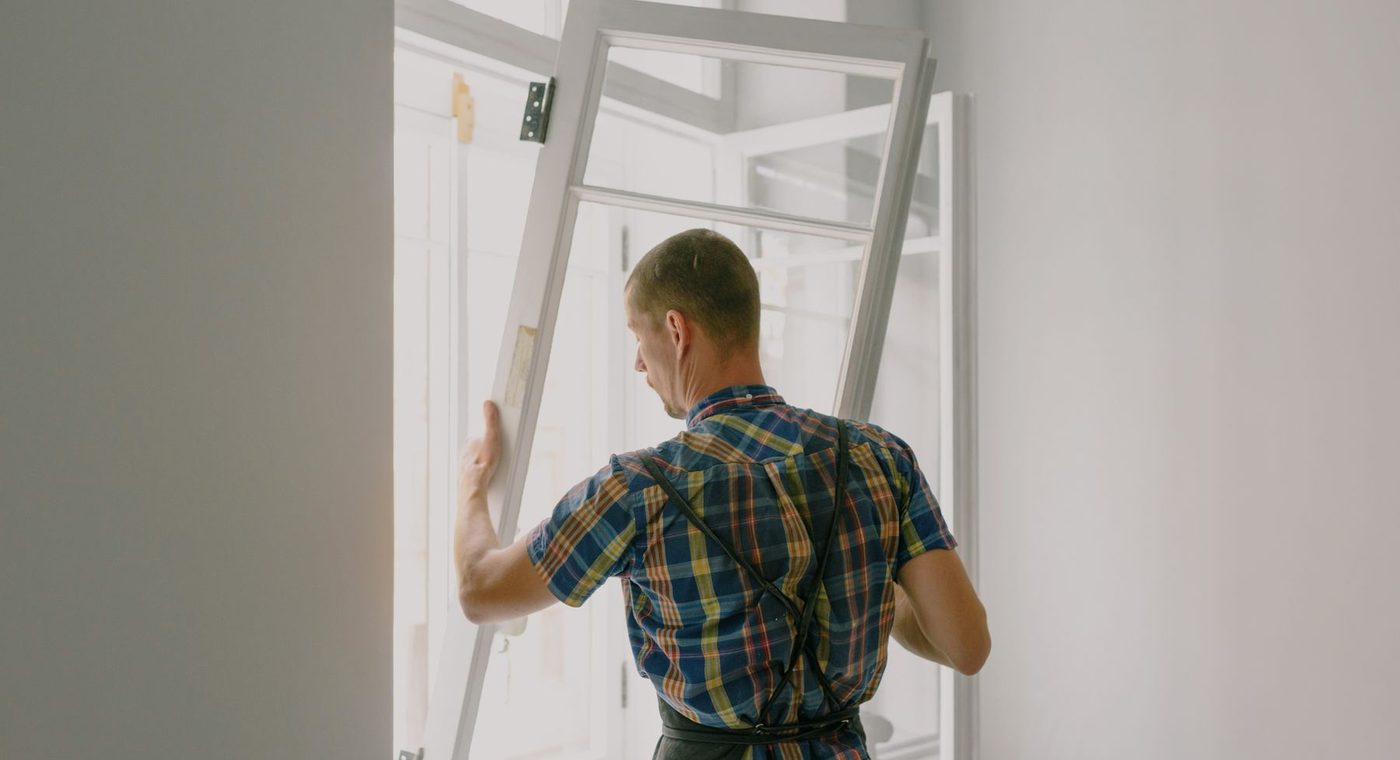 A door fitter hanging a new door leaf in its frame