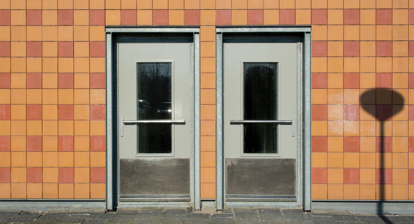 An aluminum storefront door with a surface-mounted closer being adjusted
