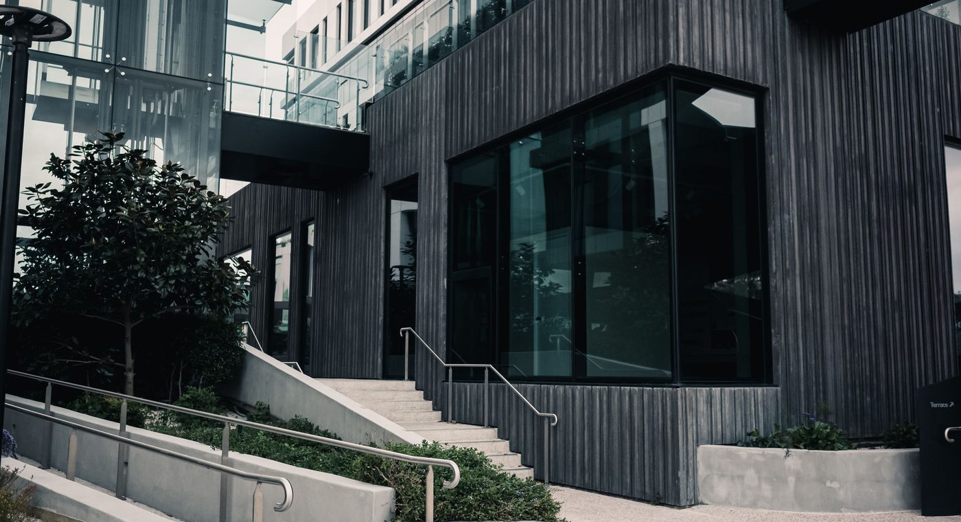A finished modern building entrance with black-framed glass doors and steps
